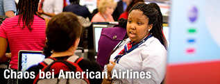 Angestellte der American Airlines spricht mit Passagieren