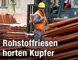 Arbeiter einer Kupfermine in Chile zwischen gelagerten Kupferkathoden