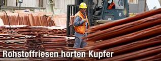 Arbeiter einer Kupfermine in Chile zwischen gelagerten Kupferkathoden