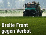 Traktor versprüht auf einem Feld Pestizid