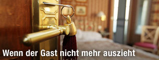 Geöffnete Tür mit Schlüssel führt zu einem Hotelzimmer