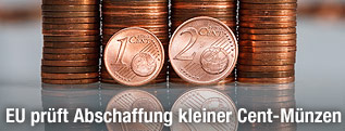 Eine Ein-Cent- und eine Zwei-Cent-Münze vor mehreren Stapeln Cent-Münzen