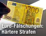 Eine Hand hält einen gefälschten 200-Euro-Schein gegen eine Lampe