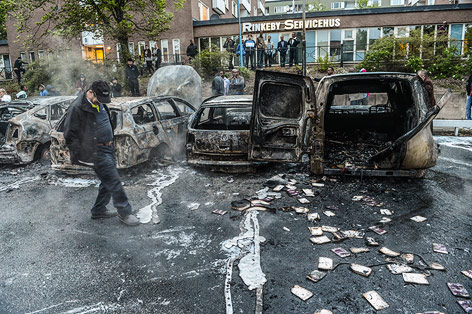 © AP/Scanpix/Fredrik Sandberg Schaulustiger bei abgebrannten Autowracks
