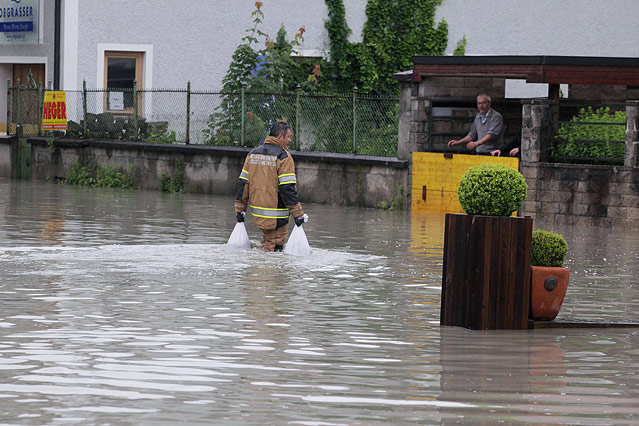 © APA/RUBRA/Rudolf Brandstätter Ein Feuerwehrmann watet mit Säcken durch knietiefes Wasser