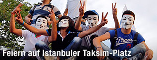 Jugendliche mit Guy-Fawkes-Masken zeigen Victory-Zeichen