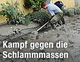 Ein Mann schaufelt im Garten Schlamm weg