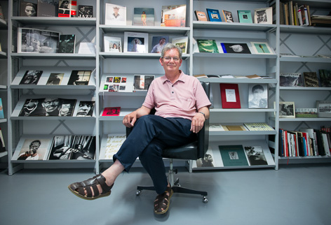 © Philipp Naderer Portraitfoto von Martin Parr, sitzend vor Buchregal