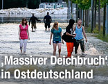 Menschen überqueren eine überschwemmte Straße