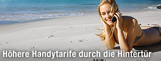 Frau liegt auf dem Strand und telefoniert mit Handy