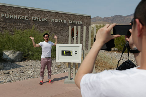 Touristen fotografieren sich vor einer Temperaturanzeige mit 127 Fahrenheit