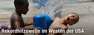 Kinder spielen am Wasserhydranten