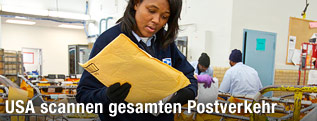 Mitarbeiterin des United States Postal Service h&auml;lt einen Brief in der Hand