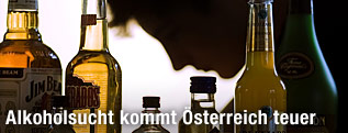 Mann senkt Kopf hinter Alkoholflaschen