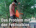 Zwei Männer urinieren in ein an einem Baum angebrachtes Pissoir