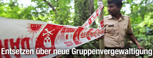 Polizeiabsperrung und indischer polizist beim Tatort