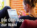 Junge Frau sieht sich auf einem iPad die ORF-Wahl-App an