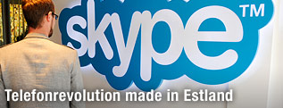 Mann steht vor einem Skype-Logo