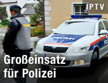 Polizist neben einem Polizeiauto