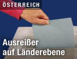 Eine Hand wirft einen Wahlzettel in eine Urne
