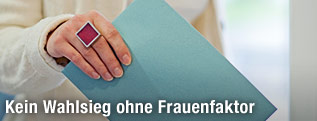 Eine Frau h&auml;lt ein Wahlkuvert in der Hand