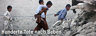 Kinder gehen durch Tr&uuml;mmer nach einem Erdbeben
