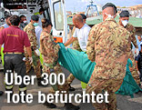 Soldaten heben einen Leichensack in einen Rettungswagen