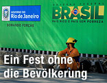 Bauarbeiter sitzt vor einem Brasilien-Poster auf dem Boden