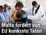 Ein geretteter Flüchtling wird von einem Boot herunterbegleitet