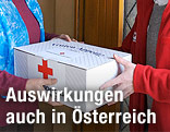 Ein Rot-Kreuz-Mitarbeiter gibt ein Essenspaket aus