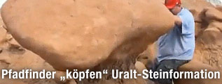 Ein Pfadfinder wirft eine alte Felsformation um