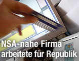 Hand mit E-Card vor Computerbildschirm
