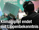 Ein Teilnehmer des UNO-Weltklimagipfels in Warschau hält einen Zettel in die Höhe