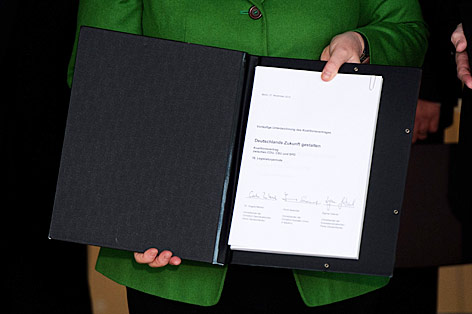 Angela Merkel zeigt den Koalitionsvertrag mit drei Unterschriften
