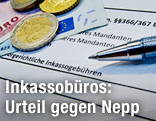 Geld liegt auf einem Schreiben eines Inkassobüros mit einer Schuldenaufstellung