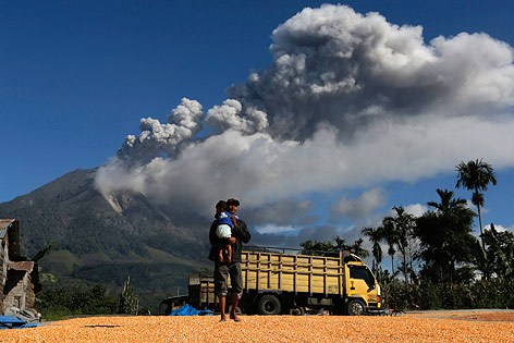 © Reuters/Beawiharta Ein Mann trägt ein Kind vor dem Vulkan am Berg Sinabung