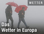 Zwei Männer mit Regenschirm im Nebel