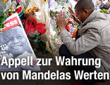 Ein Mann trauert neben einem Bild von Nelson Mandela