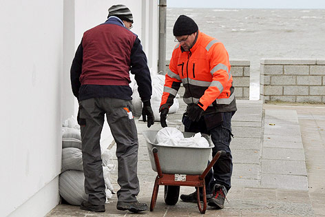 © APA/EPA/Hans-Christian Woestel Zwei Männer türmen Sandsäcke auf