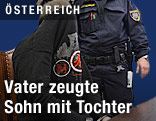 Verurteilter neben Polizisten im Verhandlungssaal