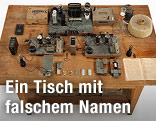 Arbeitstisch mit Paraffinblock, Geiger-Müller-Zähler, Batterien, Saugflasche und Protokollheft