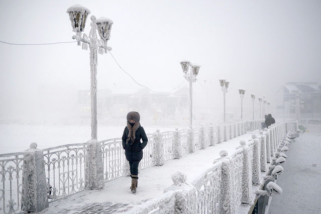 © picturedesk.com/Rex Features/Amos Chapple Eine warm angezogene Frau geht durch eine tiefwinterliche Landschaft in Oimjakon