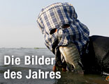 Fischer mit Fisch im Mund