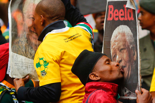 © Reuters/Kai Pfaffenbach Menschen beim Küssen von Mandela-Plakaten