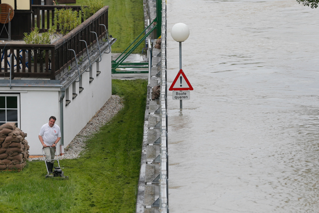 © Reuters/Leonhard Foeger Man mäht den Rasen neben Hochwasserschutzdamm