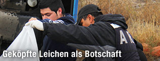 Mexikanische Polizisten schauen unter eine Leichendecke