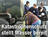 Menschen füllen Trinkwasser aus einem Tank in ihre Kanister