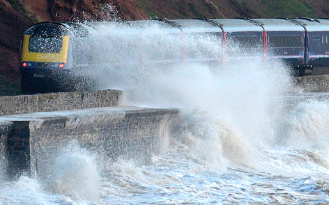 © Reuters/Toby Melville Wellen brechen an der Küste neben einem vorbeifahrenden Zug in Devon, Südwestengland
