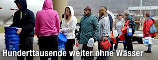 Menschen mit Kanistern stellen sich für Trinkwasser an