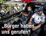 Mitglieder einer Bürgerwehr halten zwei Polizisten fest